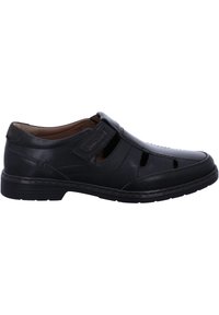 Black leather shoe with cut-out design, featuring a wide strap across the top. Smooth texture, rounded toe, and cushioned interior.