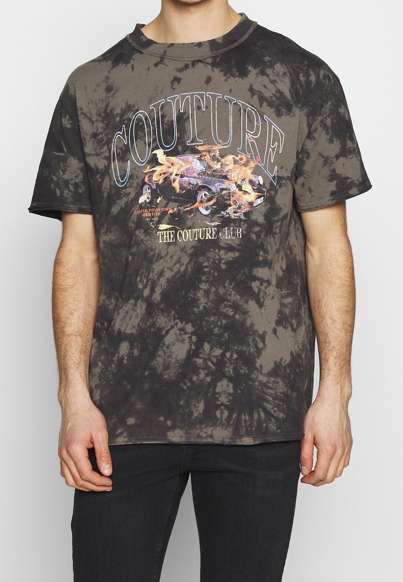 Grafická trička vyrobená z bavlny, s potiskem tie-dye v tmavě šedé barvě. Na přední straně je zobrazeno barevné grafické auto s plameny a výrazným textem.