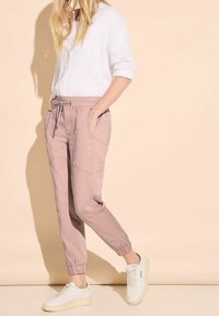 Lightweight, pink jogger pants with elastic cuffs and drawstring waist, paired with a white, long-sleeve, button-up shirt.
