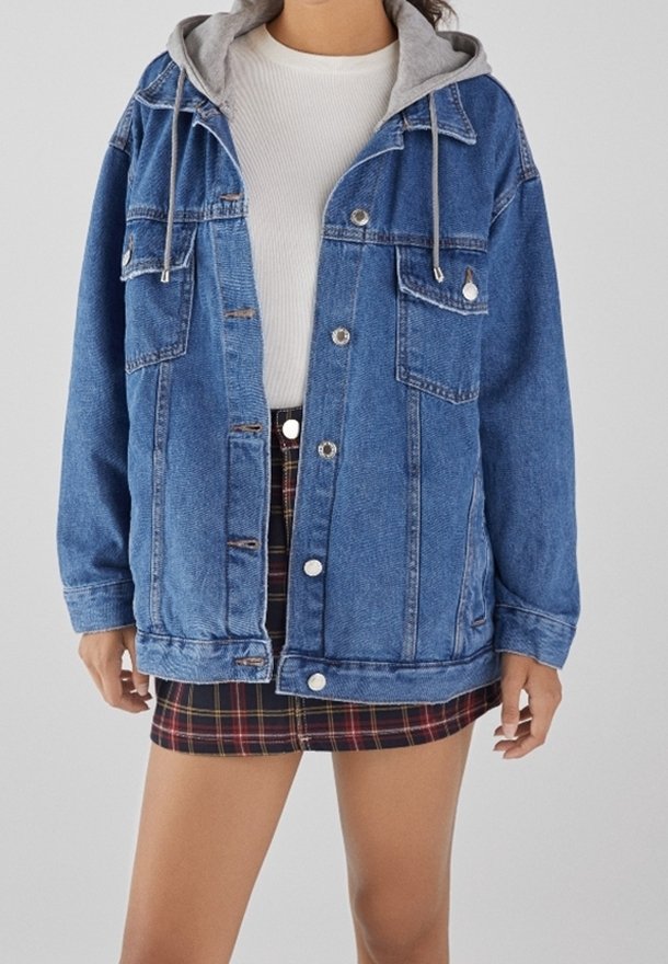 Spijkerjack met een grijze capuchon, twee voorzakken, knoopsluiting en een losse pasvorm. Gecombineerd met een geruite mini-rok.