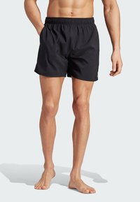 Black swim shorts with an elastic waistband, side pockets, and a smooth texture. Designed for comfort and ease of movement.