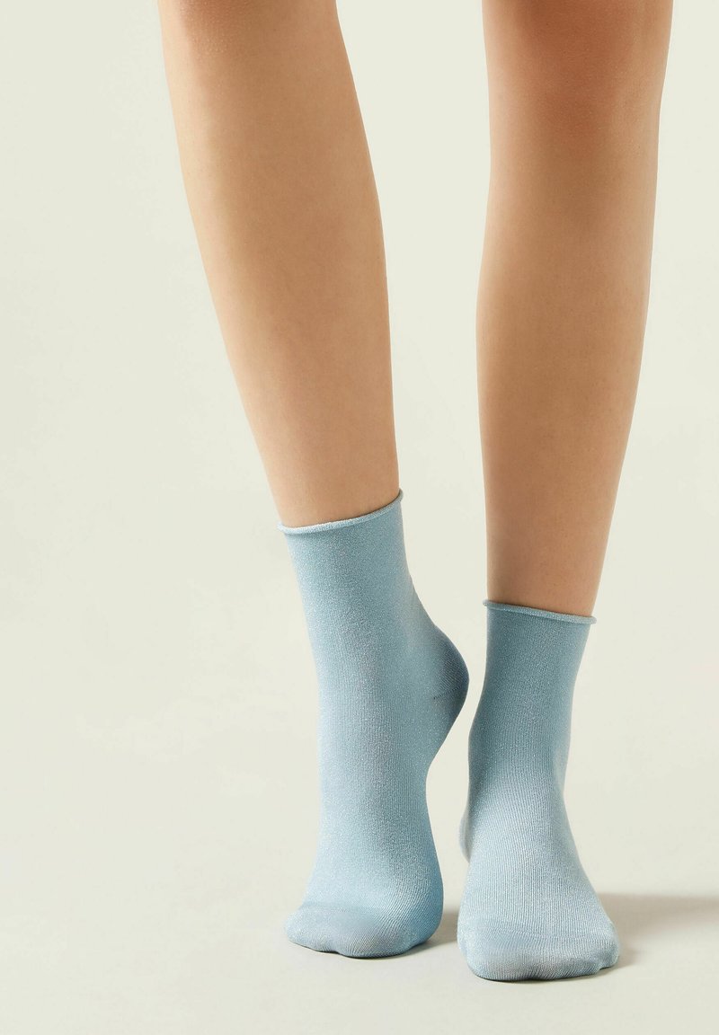 Helles blaues Knöchelsocken aus einem weichen, glatten Stoff mit einem gerippten Bund, der eine leicht glänzende Textur und eine enge Passform aufweist.