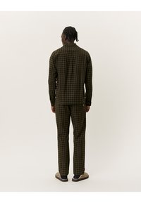 Hnědá a zelená kostkovaná košile s odpovídajícími kalhotami, vyrobená z měkké látky. Má rovný střih a casual fit, vhodné pro volné nošení.