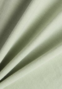 Lichtgroene stof met een gladde textuur, met zachte plooien en een consistente, gelijkmatige weving overal. Geen duidelijke patronen of accenten.