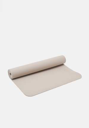 Tapete de yoga bege com uma superfície texturizada, enrolado parcialmente, apresentando um padrão subtil e um logótipo da marca ao longo de uma das bordas.