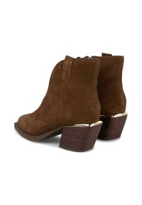 Botas de ante marrón hasta el tobillo con un tacón apilado y acentos metálicos. Presentan costuras decorativas y un cierre de cremallera en el lateral.