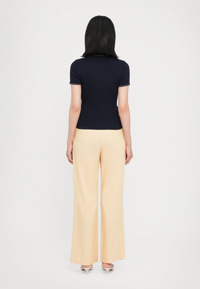 Navy ribbed short-sleeve top paired with light yellow wide-leg trousers, featuring a smooth texture and subtle color contrast.