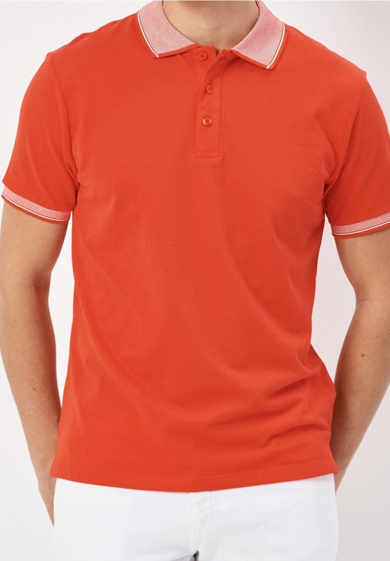 Polo rouge avec un col texturé à rayures blanches, une patte de boutonnage à deux boutons et des manches courtes avec des accents rayés assortis.