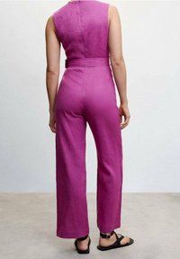 Combinez un combinaisons magenta à corsage ajusté, avec une coupe jambes larges et des détails de ceinture. Fabriqué à partir d'un tissu texturé, avec une fermeture éclair dans le dos.