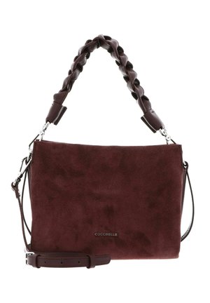 Sac à main en daim marron foncé avec anse tressée, bandoulière amovible et petit logo métallique de la marque au centre devant.