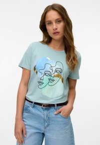 Lichtblauw T-shirt met korte mouwen, versierd met een zwarte lijntekening van twee gezichten, aangevuld met abstracte aquarelvormen in blauw en goud.