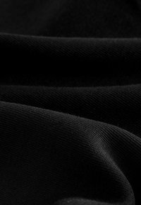 Schwarzer Stoff mit einer glatten Textur, der subtile Falten und einen leichten Glanz aufweist und ein feines, gleichmäßiges Strickmuster zeigt.