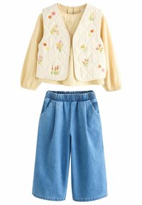 Kviltet cremet vest med blomstermotiver, parret med lyseblå denim culotter med elastisk talje og sidelommer.