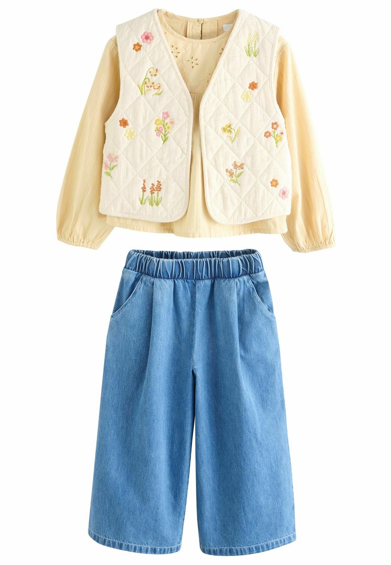 Kviltet cremet vest med blomstermotiver, parret med lyseblå denim culotter med elastisk talje og sidelommer.