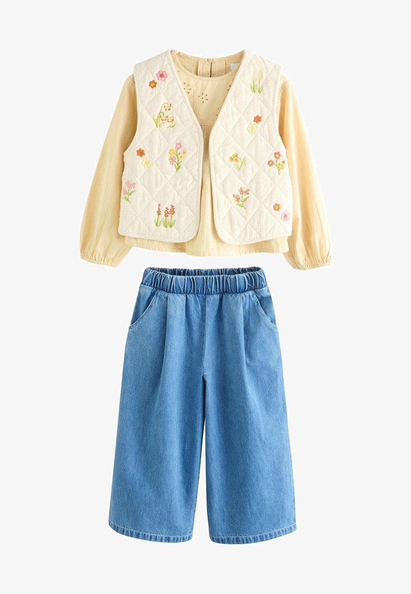 Geknopte crèmekleurige vest met bloemenborduurwerk, gecombineerd met lichtblauwe denim culottes met een elastische tailleband en zijzakken.