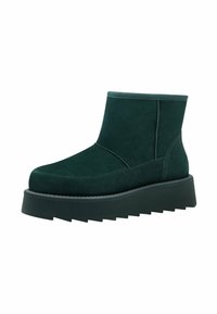 Stivaletti in suede verde con punta arrotondata e una spessa suola nera a piattaforma con un motivo a zigzag lungo i bordi.