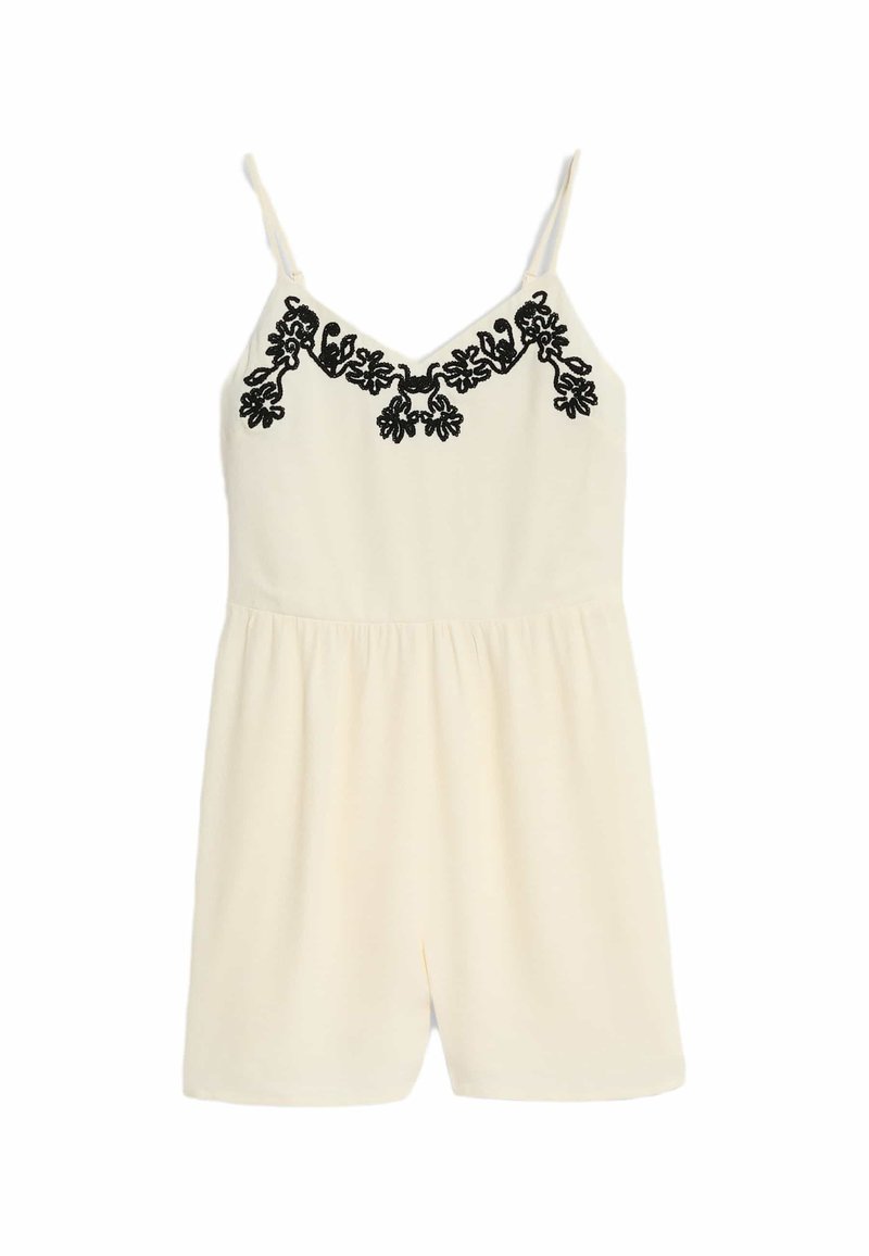 Creme jumpsuit med V-hals, tynde stropper og sort broderet blomstermønster på brystet. Blødt tekstureret stof og afslappet pasform.