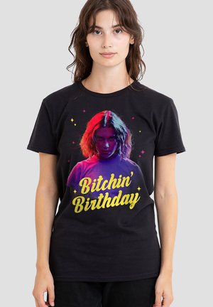 Black t-shirt featuring a graphic design with a central figure and the text "Bitchin' Birthday" in gold. The graphic includes colorful accents.