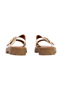 Paire de sandales marron clair avec semelles épaisses et brides autour de la cheville ornées de boucles en forme de fleurs, vues de dos sur fond blanc.