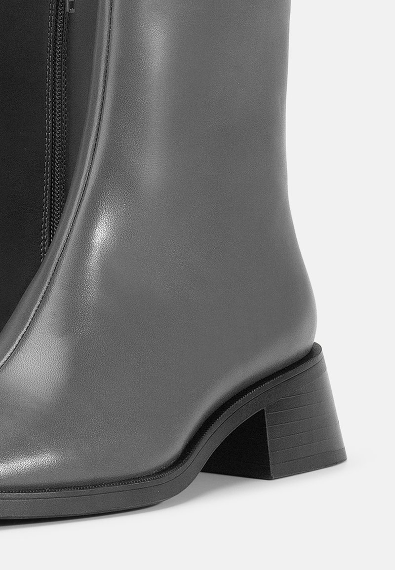 Gray leather ankle boot with a smooth finish, side zipper detail, and a stacked low heel. Textured outsole for grip.