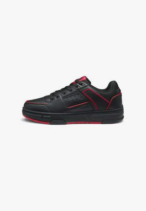 Black low-top sneaker with red accents, perforated side panel, lace-up closure, and textured sole for casual wear.