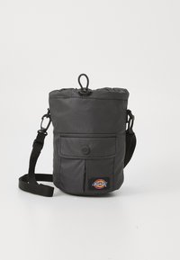 Zwarte stoffen schoudertas met een geplooide bovenkant, voorvak, verstelbare schouderband en een logopatch. Gladde textuur met minimale details.