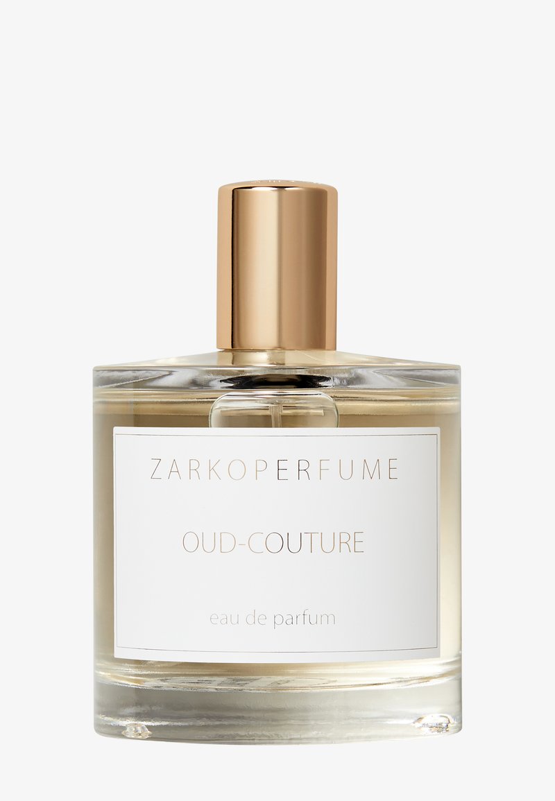 Ronde glazen parfumfles met gouden dop, gelabeld "Zarkoperfume Oud-Couture eau de parfum" met lichte amberkleurige vloeistof binnenin.