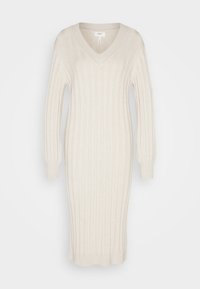 Brede gebreide jurk in zacht beige, met een V-hals en lange mouwen. Heeft verticale ribbels, een aangesloten silhouet en een lengte onder de knie.
