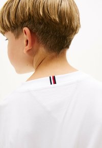 Weißes Baumwoll-T-Shirt mit einem kontrastierenden Streifen in Rot und Marineblau am Nacken. Weiche Textur mit klassischer Passform.