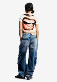 Grafické tričko s veľkým potlačeným motívom úst, krátke rukávy. Kombinované s voľnejšími svetlomodrými denimovými cargo nohavicami s vreckami a vyblednutým efektom.