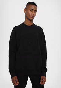 Sort sweatshirt med et tekstureret, prægede logo foran. Har rund hals og ribbede manchetter. Lavet af en blød bomuldsblanding.