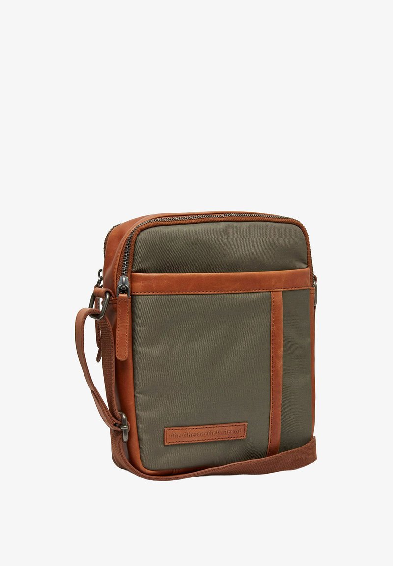 Borsa a tracolla in tessuto verde con dettagli in pelle marrone. Presenta una chiusura con zip, una tracolla regolabile e una tasca frontale con logo.