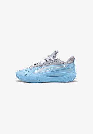 Lyseblå og grå atletiksneaker med hvide snørebånd, polstret sål og hvidt mærkelogo på siden vist fra venstre profil.