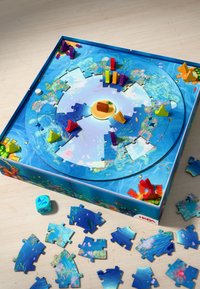 Round board game with colorful plastic pieces in yellow, red, purple, and green. Features blue water-themed graphics and puzzle pieces scattered nearby.