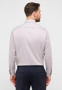 Lichtpaars overhemd met lange mouwen, gestructureerde stof, manchetten met knopen en een klassieke kraag, gecombineerd met een donkere broek.