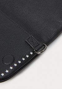 Pochette en cuir noir avec une surface texturée, accents d'étoiles en argent le long du bord et un attaches en métal. Aucun branding visible.