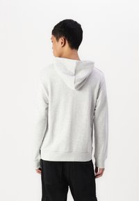 Grauer Kapuzenpullover aus weichem Stoff, mit Kordelzug-Kapuze, Rippbündchen und Saum, lockerer Passform und ohne sichtbare Muster.