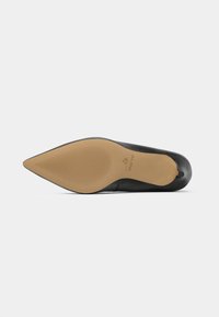 Scarpa nera con tacco alto e punta affusolata, superiore in pelle liscia, suola in gomma e logo inciso sulla suola, con linee di trazione scanalate.