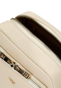 Borsa zip in pelle beige con finitura testurizzata, caratterizzata da hardware dorato e una forma rettangolare elegante. Due scomparti con zip visibili.