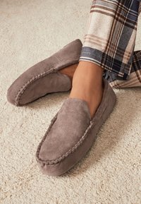 Grau Wildleder Loafers mit weicher Textur, versehen mit dekorativen Nähten entlang der Kanten. Die Schuhe haben ein flaches, abgerundetes Design.