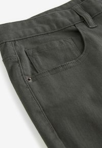 Jean en denim gris foncé en gros plan montrant la poche avant, la poche à monnaie, le passant de ceinture et le détail des rivets métalliques.