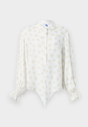 Λευκό μπλουζάκι με μακριά μανίκια με κίτρινα και λευκά σχέδια μαργαρίτας, εμπρόσθιο κλείσιμο με κουμπιά, αιχμηρή περικοπή και σούρες στις μανσέτες.