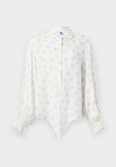 Λευκό μπλουζάκι με μακριά μανίκια με κίτρινα και λευκά σχέδια μαργαρίτας, εμπρόσθιο κλείσιμο με κουμπιά, αιχμηρή περικοπή και σούρες στις μανσέτες.