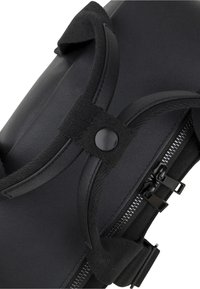 Black cylindrical bag made of textured synthetic material. Features a zip closure and black snap fasteners. Adjustable nylon straps are visible.