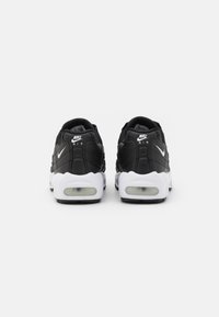Crni Nike Air tenisice s bijelim detaljima, s gornjim dijelom od teksturirane tkanine, vidljivim zračnim jastučićima u potplatu i podstavljenim ovratnikom.