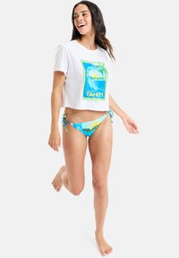 Cropped white t-shirt with a colorful "Tahiti" graphic; matching blue bikini with adjustable ties. Both are made from lightweight, soft fabric.