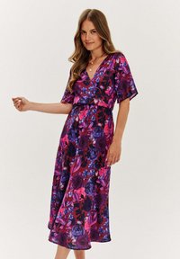 Kwiatowa sukienka o luźnym kroju, z intensywną fioletową bazą i różowo-niebieskimi różami, z krótkimi rękawami i zwiewną długością midi. Miękki, lekki materiał.