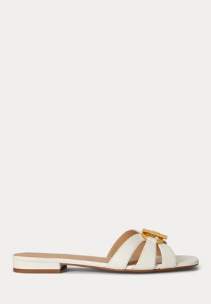 Biała płaska sandałka na płaskiej podeszwie z trzema skórzanymi paskami i złotą dekoracyjną klamrą w stylu bambusowym na białym tle.