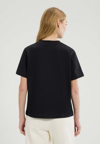 Czarny t-shirt z krótkim rękawem wykonany z bawełny, z klasycznym dekoltem typu crew i prostym wykończeniem hemu. Prosty, jednolity kolor bez wzorów.