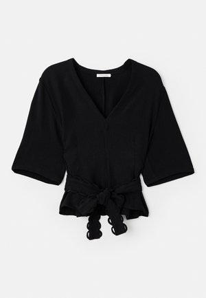 Musta peplum-paitaSyvällä V-puolella, lyhyillä hihoilla ja sidottu vyötärö. Teksturoitu kangas ja aaltoileva reunus vyössä.
